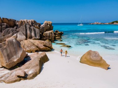 Anse Cocos plajı, La Digue Adası, Seyshelles, La Digue Seychelles kuş bakışı drone görüntüsü, günbatımında kumsalda yürüyen birkaç erkek ve kadın lüks bir tatilde.