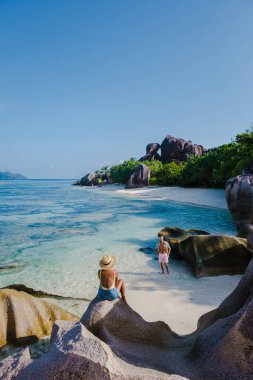 Anse Source dArgent plajı, La Digue Adası, Seyshelles, İHA hava görüntüsü La Digue Seyşelles kuş bakışı, gün batımında sahilde yürüyen birkaç erkek ve kadın lüks bir tatilde