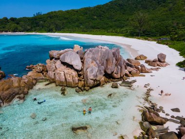 Anse Cocos plajı, La Digue Adası, Seyshelles, La Digue Seychelles kuş bakışı drone görüntüsü, günbatımında kumsalda yürüyen birkaç erkek ve kadın lüks bir tatilde.
