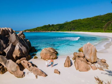 Anse Cocos plajı, La Digue Adası, Seyshelles, La Digue Seychelles kuş bakışı drone görüntüsü, günbatımında kumsalda yürüyen birkaç erkek ve kadın lüks bir tatilde.