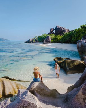Anse Source dArgent plajı, La Digue Adası, Seyshelles, İHA hava görüntüsü La Digue Seyşelles kuş bakışı, gün batımında sahilde yürüyen birkaç erkek ve kadın lüks bir tatilde