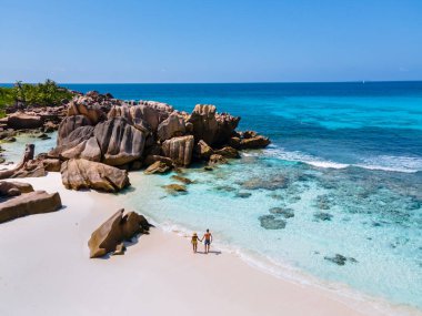Anse Cocos plajı, La Digue Adası, Seyshelles, La Digue Seychelles kuş bakışı drone görüntüsü, günbatımında kumsalda yürüyen birkaç erkek ve kadın lüks bir tatilde.