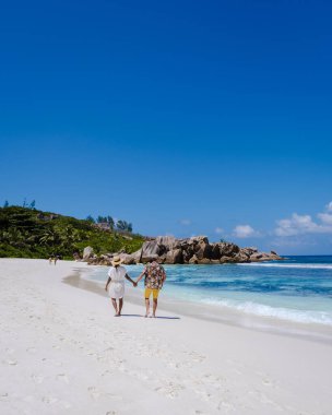 Anse Cocos plajı, La Digue Adası, Seyshelles, La Digue Seychelles kuş bakışı drone görüntüsü, günbatımında kumsalda yürüyen birkaç erkek ve kadın lüks bir tatilde.