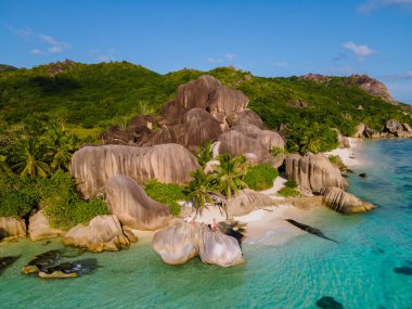 Anse Source dArgent plajı, La Digue Adası, Seyshelles, İHA hava görüntüsü La Digue Seyşelles kuş bakışı, gün batımında sahilde yürüyen birkaç erkek ve kadın lüks bir tatilde