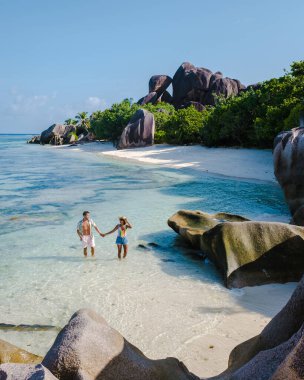 Anse Source dArgent plajı, La Digue Adası, Seyshelles, İHA hava görüntüsü La Digue Seyşelles kuş bakışı, gün batımında sahilde yürüyen birkaç erkek ve kadın lüks bir tatilde