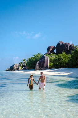 Anse Source dArgent plajı, La Digue Adası, Seyshelles, İHA hava görüntüsü La Digue Seyşelles kuş bakışı, gün batımında sahilde yürüyen birkaç erkek ve kadın lüks bir tatilde