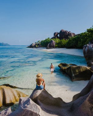 Anse Source dArgent plajı, La Digue Adası, Seyshelles, İHA hava görüntüsü La Digue Seyşelles kuş bakışı, gün batımında sahilde yürüyen birkaç erkek ve kadın lüks bir tatilde