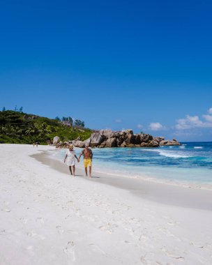 Anse Cocos plajı, La Digue Adası, Seyshelles, La Digue Seychelles kuş bakışı drone görüntüsü, günbatımında kumsalda yürüyen birkaç erkek ve kadın lüks bir tatilde.