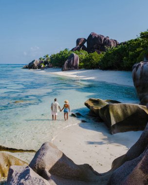 Anse Source dArgent plajı, La Digue Adası, Seyshelles, İHA hava görüntüsü La Digue Seyşelles kuş bakışı, gün batımında sahilde yürüyen birkaç erkek ve kadın lüks bir tatilde