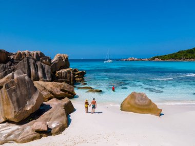 Anse Cocos plajı, La Digue Adası, Seyshelles, La Digue Seychelles kuş bakışı drone görüntüsü, günbatımında kumsalda yürüyen birkaç erkek ve kadın lüks bir tatilde.