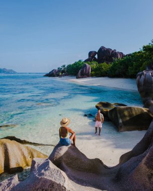 Anse Source dArgent plajı, La Digue Adası, Seyshelles, İHA hava görüntüsü La Digue Seyşelles kuş bakışı, gün batımında sahilde yürüyen birkaç erkek ve kadın lüks bir tatilde