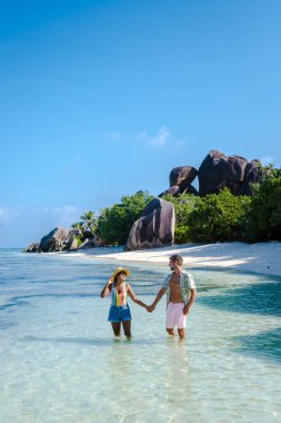 Anse Source dArgent plajı, La Digue Adası, Seyshelles, İHA hava görüntüsü La Digue Seyşelles kuş bakışı, gün batımında sahilde yürüyen birkaç erkek ve kadın lüks bir tatilde