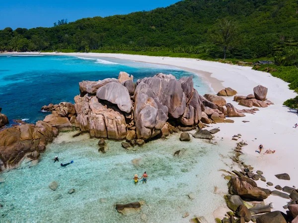 Anse Cocos plajı, La Digue Adası, Seyshelles, La Digue Seychelles kuş bakışı drone görüntüsü, günbatımında kumsalda yürüyen birkaç erkek ve kadın lüks bir tatilde.