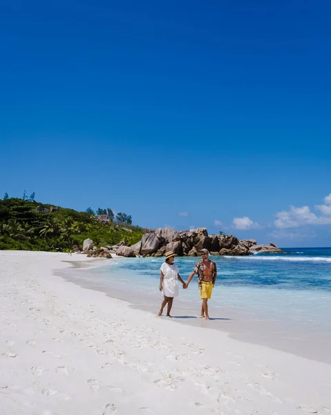 Anse Cocos海滩、 La Digue岛、 Seyshelles 、 Drone鸟瞰La Digue塞舌尔的鸟瞰景观，一对男女在日落时在海滩上散步，享受奢华假期 — 图库照片