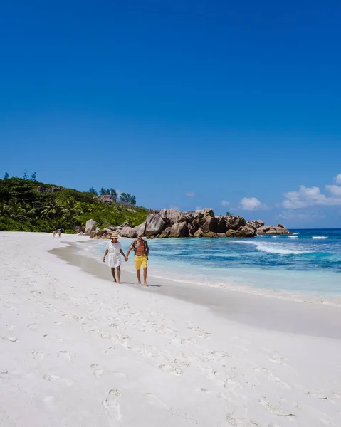 Anse Cocos παραλία, La Digue Island, Seyshelles, Drone εναέρια άποψη της La Digue Σεϋχέλλες πουλί θέα, ζευγάρι άνδρες και γυναίκες με τα πόδια στην παραλία κατά τη διάρκεια του ηλιοβασιλέματος σε πολυτελείς διακοπές — Φωτογραφία Αρχείου