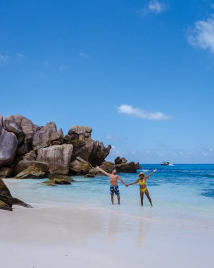 Anse Cocos plajı, La Digue Adası, Seyshelles, La Digue Seychelles kuş bakışı drone görüntüsü, günbatımında kumsalda yürüyen birkaç erkek ve kadın lüks bir tatilde.