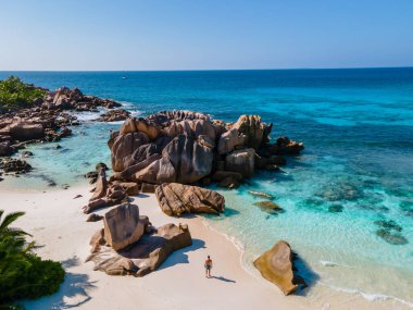 Anse Cocos plajı, La Digue Adası, Seyshelles, La Digue Seychelles kuş bakışı drone görüntüsü, günbatımında kumsalda yürüyen birkaç erkek ve kadın lüks bir tatilde.