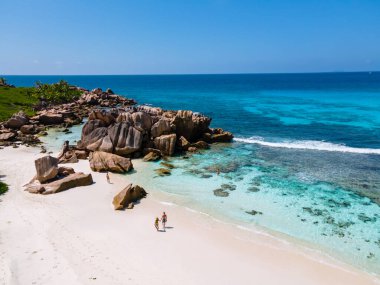 Anse Cocos plajı, La Digue Adası, Seyshelles, La Digue Seychelles kuş bakışı drone görüntüsü, günbatımında kumsalda yürüyen birkaç erkek ve kadın lüks bir tatilde.