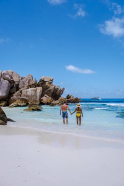 Anse Cocos plajı, La Digue Adası, Seyshelles, La Digue Seychelles kuş bakışı drone görüntüsü, günbatımında kumsalda yürüyen birkaç erkek ve kadın lüks bir tatilde.