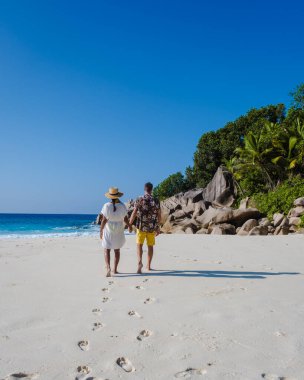 Anse Cocos plajı, La Digue Adası, Seyshelles, La Digue Seychelles kuş bakışı drone görüntüsü, günbatımında kumsalda yürüyen birkaç erkek ve kadın lüks bir tatilde.