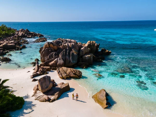 Anse Cocos plajı, La Digue Adası, Seyshelles, La Digue Seychelles kuş bakışı drone görüntüsü, günbatımında kumsalda yürüyen birkaç erkek ve kadın lüks bir tatilde.