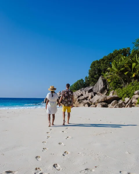 Пляж Анс-Кокос, остров Ла-Дигю, Сейшелы, вид дрона с высоты птичьего полета на Ла-Дигу Сейшелы, пара мужчин и женщин, гуляющих на пляже во время заката во время роскошного отпуска — стоковое фото
