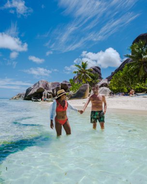 Anse Source dArgent plajı, La Digue Adası, Seyshelles, İHA hava görüntüsü La Digue Seyşelles kuş bakışı, gün batımında sahilde yürüyen birkaç erkek ve kadın lüks bir tatilde