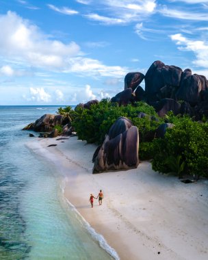 Anse Source dArgent plajı, La Digue Adası, Seyshelles, İHA hava görüntüsü La Digue Seyşelles kuş bakışı, gün batımında sahilde yürüyen birkaç erkek ve kadın lüks bir tatilde