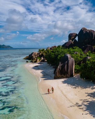 Anse Source dArgent plajı, La Digue Adası, Seyshelles, İHA hava görüntüsü La Digue Seyşelles kuş bakışı, gün batımında sahilde yürüyen birkaç erkek ve kadın lüks bir tatilde