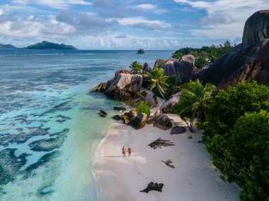 Anse Source dArgent plajı, La Digue Adası, Seyshelles, İHA hava görüntüsü La Digue Seyşelles kuş bakışı, gün batımında sahilde yürüyen birkaç erkek ve kadın lüks bir tatilde