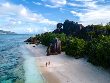 Anse Source dArgent plajı, La Digue Adası, Seyshelles, İHA hava görüntüsü La Digue Seyşelles kuş bakışı, gün batımında sahilde yürüyen birkaç erkek ve kadın lüks bir tatilde