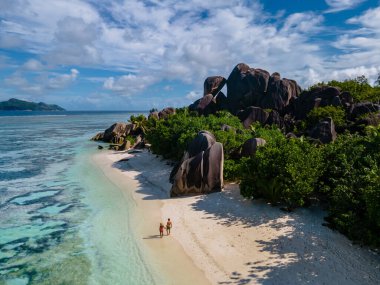 Anse Source dArgent plajı, La Digue Adası, Seyshelles, İHA hava görüntüsü La Digue Seyşelles kuş bakışı, gün batımında sahilde yürüyen birkaç erkek ve kadın lüks bir tatilde