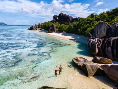 Anse Source dArgent plajı, La Digue Adası, Seyshelles, İHA hava görüntüsü La Digue Seyşelles kuş bakışı, gün batımında sahilde yürüyen birkaç erkek ve kadın lüks bir tatilde