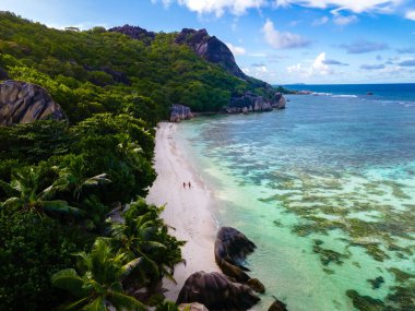 Anse Source dArgent plajı, La Digue Adası, Seyshelles, İHA hava görüntüsü La Digue Seyşelles kuş bakışı, gün batımında sahilde yürüyen birkaç erkek ve kadın lüks bir tatilde