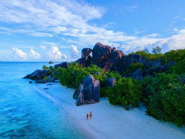 Anse Source dArgent beach, La Digue Island, Seyshelles, Drone aerial view of La Digue Seychelles bird eye view, couple men and woman walking at the beach during sunset at a luxury vacation