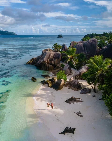 Anse Source dArgent plajı, La Digue Adası, Seyshelles, İHA hava görüntüsü La Digue Seyşelles kuş bakışı, gün batımında sahilde yürüyen birkaç erkek ve kadın lüks bir tatilde