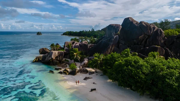 Anse Source dArgent plajı, La Digue Adası, Seyshelles, İHA hava görüntüsü La Digue Seyşelles kuş bakışı, gün batımında sahilde yürüyen birkaç erkek ve kadın lüks bir tatilde