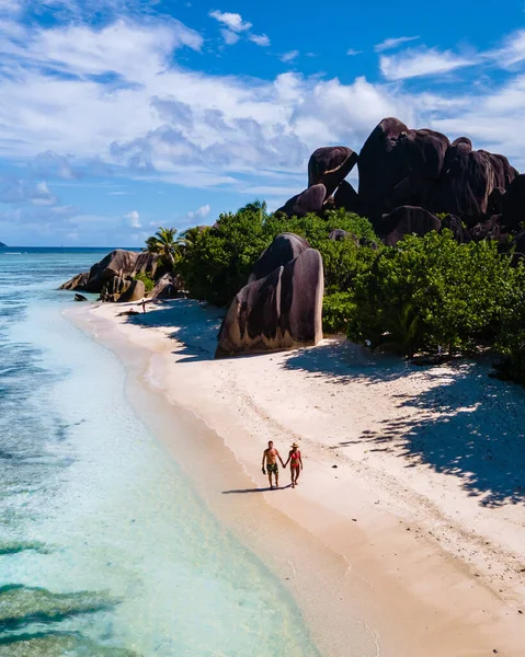 Anse Source dArgent plajı, La Digue Adası, Seyshelles, İHA hava görüntüsü La Digue Seyşelles kuş bakışı, gün batımında sahilde yürüyen birkaç erkek ve kadın lüks bir tatilde