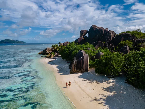 Anse Source dArgent plajı, La Digue Adası, Seyshelles, İHA hava görüntüsü La Digue Seyşelles kuş bakışı, gün batımında sahilde yürüyen birkaç erkek ve kadın lüks bir tatilde