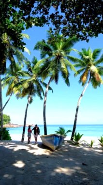 Anse Takamaka plajı Mahe Seyşeller, palmiye ağaçları ve mavi okyanuslu tropikal plaj, kumsaldaki çift ve kadın.