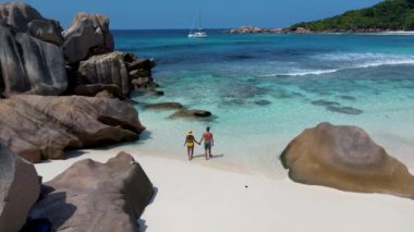 Anse Cocos plajı, La Digue Adası, Seyshelles, La Digue Seychelles kuş bakışı drone görüntüsü, günbatımında kumsalda yürüyen birkaç erkek ve kadın lüks bir tatilde.