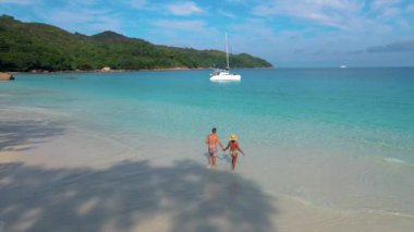 Praslin Seychelles tropical island with withe beaches and palm trees, couple men and women mid age on vacation at the Seychelles visiting the tropical beach of Anse Lazio Praslin Seychelles drone view