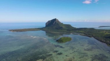 Le Morne plajı Mauritius, Tropikal plaj palmiye ağaçları ve beyaz kum mavisi okyanus ve şemsiyeli plaj yatakları, güneş sandalyeleri ve güneş şemsiyeleri bir palmiye ağacının altında, Le Morne plajı Mauritius 'ta.