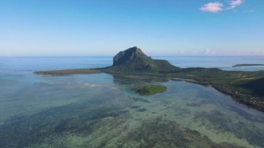 Le Morne plajı Mauritius, Tropikal plaj palmiye ağaçları ve beyaz kum mavisi okyanus ve şemsiyeli plaj yatakları, güneş sandalyeleri ve güneş şemsiyeleri bir palmiye ağacının altında, Le Morne plajı Mauritius 'ta.