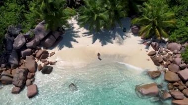 Praslin Seyşeller tropikal adası, plajları geniş ve palmiye ağaçları olan, orta yaşlı birkaç erkek ve kadın tatilde Seyşeller 'de tropikal Anse Lazio Praslin Seyşeller' in insansız hava aracı manzaralı plajını ziyaret ediyor.
