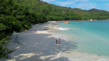 Praslin Seychelles tropical island with withe beaches and palm trees, couple men and women mid age on vacation at the Seychelles visiting the tropical beach of Anse Lazio Praslin Seychelles drone view