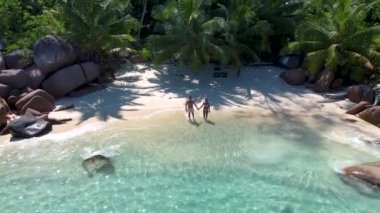 Praslin Seyşeller tropikal adası, plajları geniş ve palmiye ağaçları olan, orta yaşlı birkaç erkek ve kadın tatilde Seyşeller 'de tropikal Anse Lazio Praslin Seyşeller' in insansız hava aracı manzaralı plajını ziyaret ediyor.