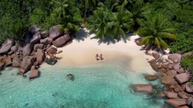 Praslin Seyşeller tropikal adası, plajları geniş ve palmiye ağaçları olan, orta yaşlı birkaç erkek ve kadın tatilde Seyşeller 'de tropikal Anse Lazio Praslin Seyşeller' in insansız hava aracı manzaralı plajını ziyaret ediyor.