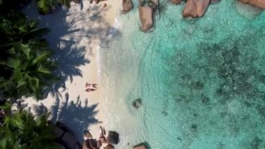 Praslin Seychelles tropical island with withe beaches and palm trees, couple men and women mid age on vacation at the Seychelles visiting the tropical beach of Anse Lazio Praslin Seychelles drone view