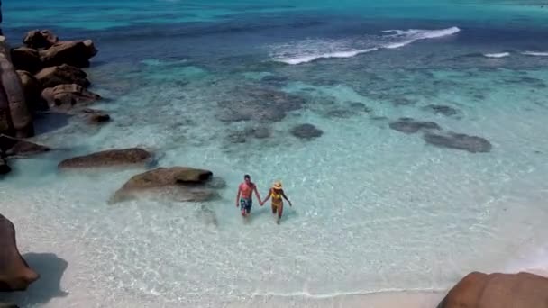 Anse Cocos海滩、 La Digue岛、 Seyshelles 、 Drone鸟瞰La Digue塞舌尔的鸟瞰景观，一对男女在日落时在海滩上散步，享受奢华假期 — 图库视频影像
